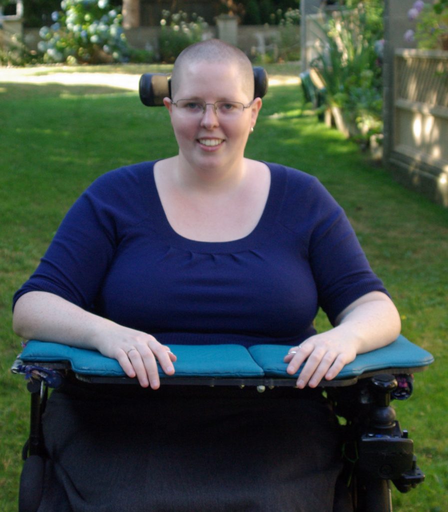 Photo of Heather in wheelchair with arms resting on a tray.